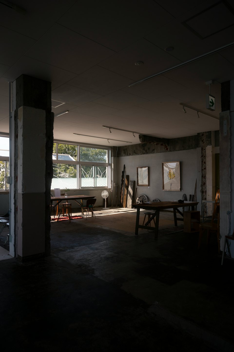 Industrieller Studiobereich mit Holztischen und abstrakter Kunst.